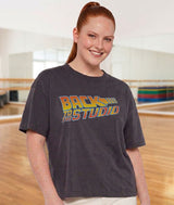 Dance teacher wearing a vintage black t-shirt with 'Back to the Studio' text in a dance studio setting