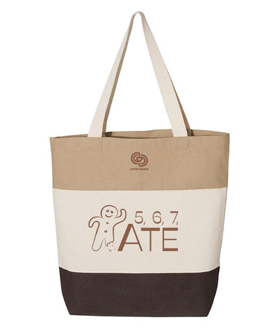 A tote bag multi-colored with shades of brown, an illustration of a gingerbread man, and the text "5, 6, 7, ATE"