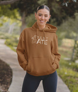 Dancer wearing a brown hoodie with 5, 6, 7, ATE graphic on her way to the studio.