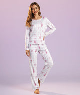 Dancer wearing a white pajama set with pointe shoes and ribbon bows on a pink grid background