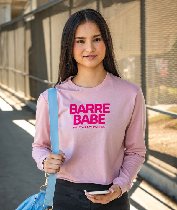 Dancer wearing long sleeve pink Barre Babe tee carrying dance bag and phone