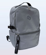 A gray backpack with black straps, zippers, and a Covet Dance logo on the front, shown against a light gray gradient background.