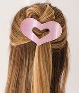 Large heart-shaped hair claw clip in a half up-do hairstyle on a plain background
