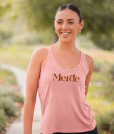 Dancer wearing a Covet Dance pink tank top with 'Merde' printed on it, standing outdoors.