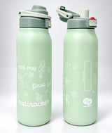 Two mint green insulated water bottles with gray lids, shown side by side on a light gray background. One bottle is labeled 'not my first nutcracker' with white line drawings, and the other shows a vertical area to write your name and a white logo near the bottom.