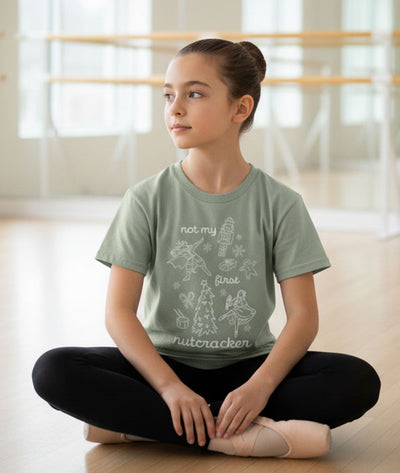Young girl in a ballet studio wearing a green t-shirt with "Not My First Nutcracker" design from Covet Dance