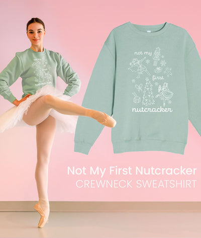 Ballerina en pointe wearing 'Not My First Nutcracker' sweatshirt with a white tutu on pink background