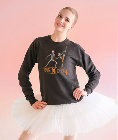Ballerina wearing a black sweatshirt with 'Pas de Doom' design from Covet Dance and a white tutu