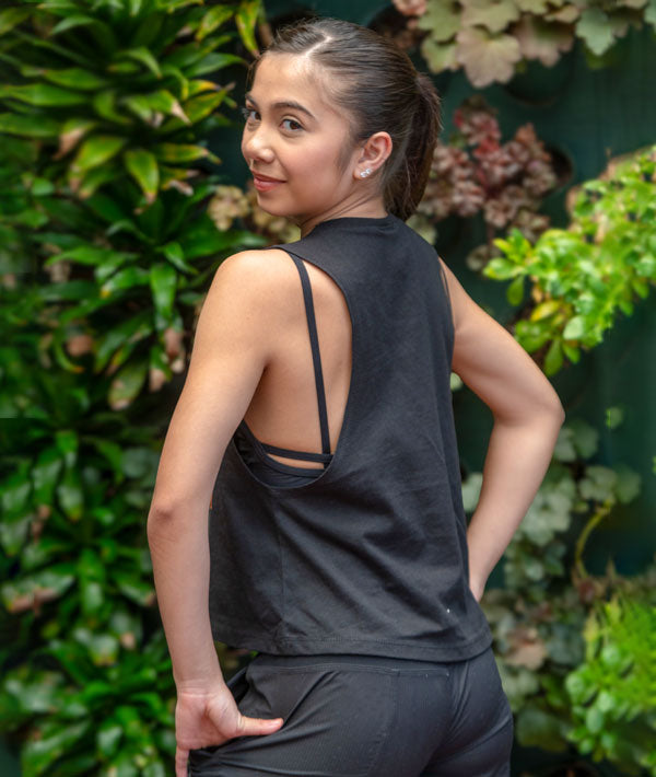 Dancer showing the back of a crop black sleeveless Covet Dance tank top