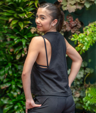 Dancer showing the back of a crop black sleeveless Covet Dance tank top