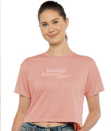 Woman wearing a peach crop t-shirt with "Resting Barre Face" on a white background
