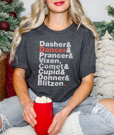 Dark gray tee with all the reindeer names on it with DANCER standing out in red while the other names are in white