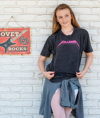 Dancer wearing a black t-shirt with pink Ballerina graphic design against a white brick wall.
