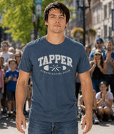Man wearing a blue Covet Dance 'Tapper' t-shirt in an outdoor setting with people around