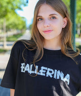 Dancer wearing a black t-shirt with 'BALLERINA' tape text outdoors.