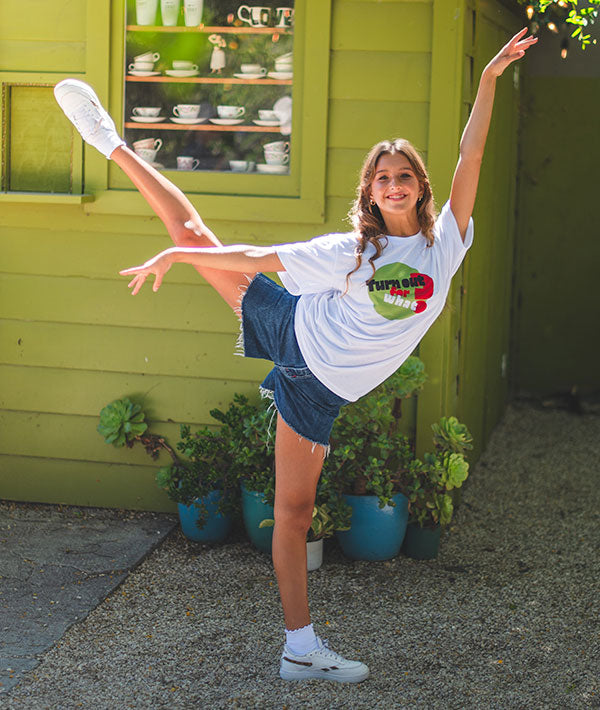 Ballerina doing an arabesque wearing a "Turn Out For What" t-shirt