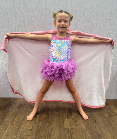 Young girl in a colorful sequin dance costume with a hooded blanket from Covet Dance