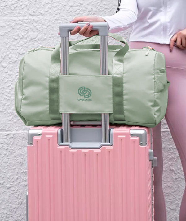 JOI Dance Duffel in mint fits has a trolley strap on the back to snugly over your suitcase handle